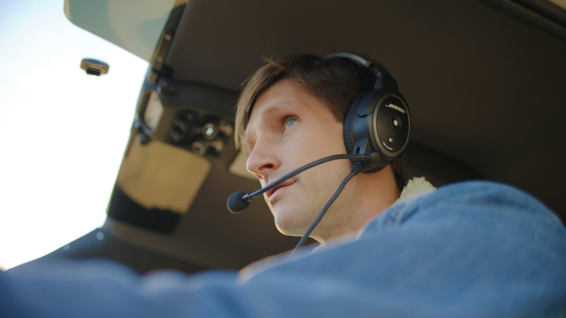 Aviation headset and push-to-talk control in a sunlit general aviation cockpit, suggesting ATC radio practice for student pilots